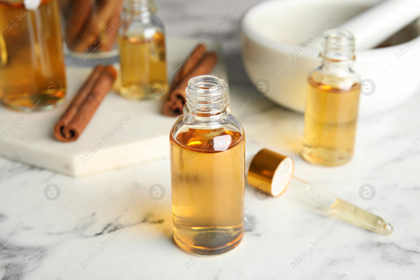 Photo of Bottles with cinnamon essential oil on marble table