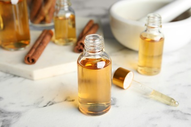 Photo of Bottles with cinnamon essential oil on marble table