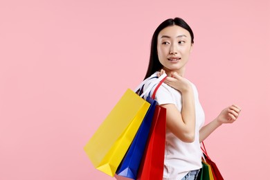 Smiling woman with shopping bags on pink background. Space for text