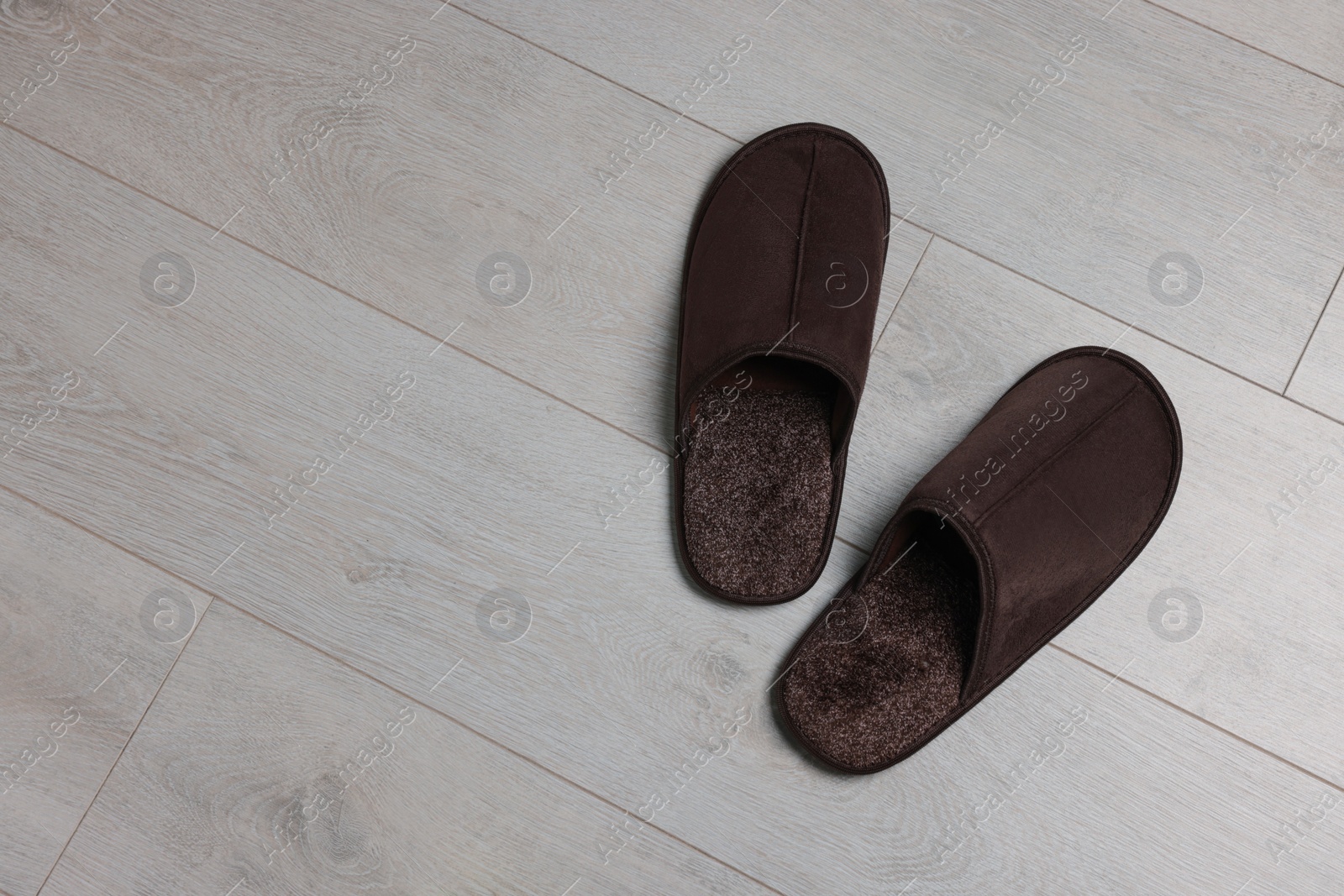 Photo of Pair of brown slippers on wooden floor, top view. Space for text