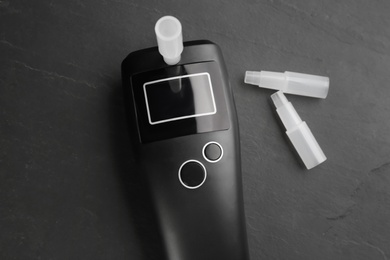Photo of Modern breathalyzer and mouthpieces on black background, flat lay