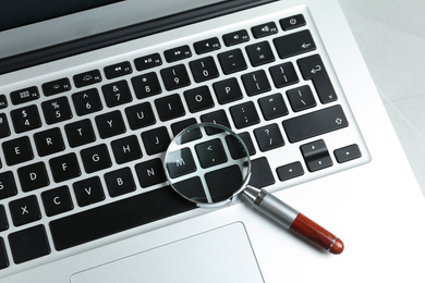 Photo of Magnifying glass and modern laptop on table, above view. Search concept