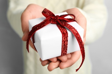 Photo of Woman holding beautiful Christmas gift on light blue background, closeup