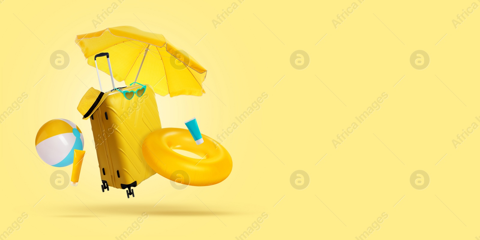 Image of Suitcase, sunscreen and beach accessories flying on pale yellow background. Banner design with space for text