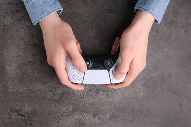 Photo of Man using wireless game controller at grey table, top view