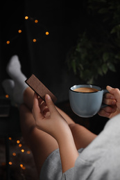 Photo of Woman with wafer and coffee on dark background, closeup. Early breakfast