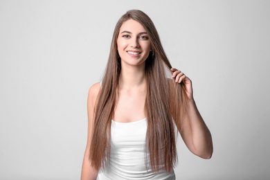 Photo of Portrait of young woman with long beautiful hair on light background