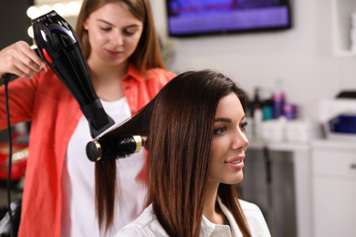 Photo of Professional hairdresser working with client in beauty salon