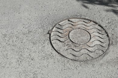 Photo of Metal sewer hatch on asphalt outdoors, space for text