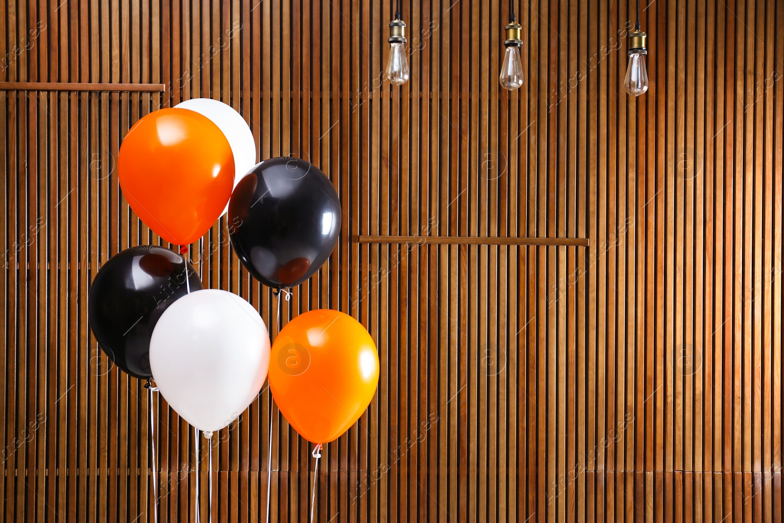 Photo of Colorful balloons against wooden wall, space for text. Halloween party