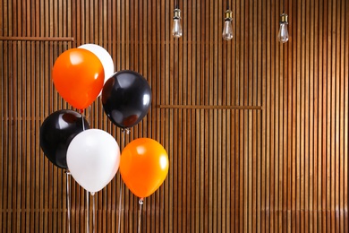 Photo of Colorful balloons against wooden wall, space for text. Halloween party