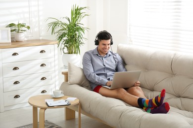 Businessman in shirt and underwear working on laptop at home