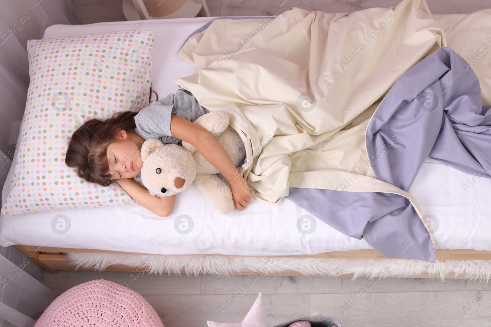 Photo of Little girl sleeping with teddy bear in bed at home