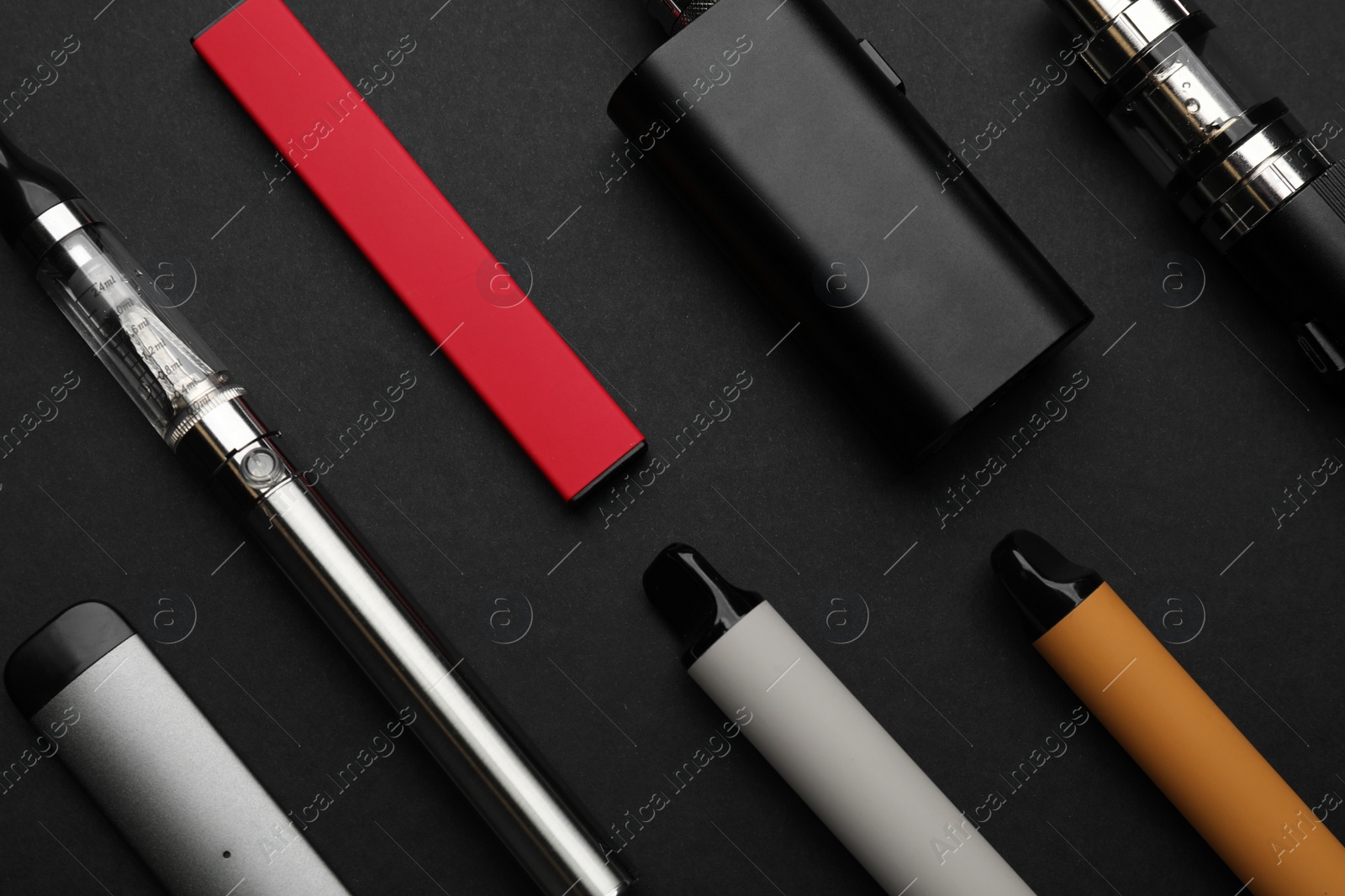 Photo of Many electronic smoking devices on black background, flat lay