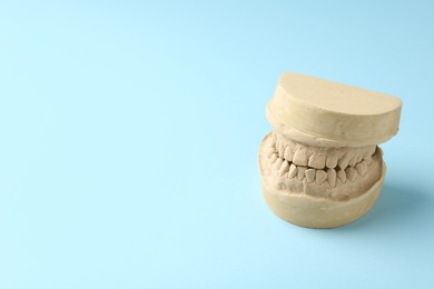 Photo of Dental model with gums on light blue background, space for text. Cast of teeth