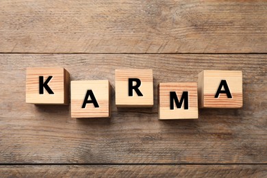 Word Karma made of cubes with letters on wooden background, top view