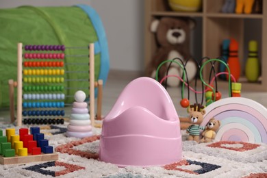 Photo of Pink baby potty and toys on carpet in room. Toilet training