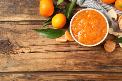 Flat lay composition with tasty tangerine jam on wooden table. Space for text