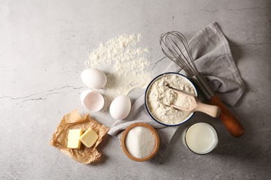 Photo of Different ingredients for dough and whisk on light textured table, flat lay