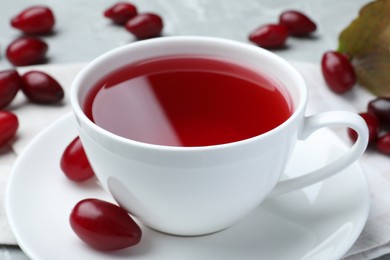 Cup of fresh dogwood tea and berries on table, closeup