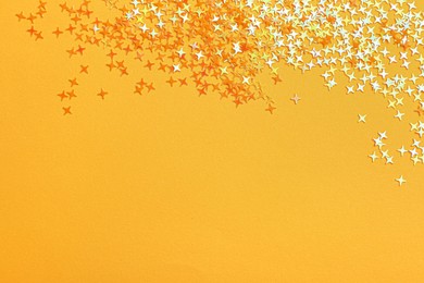 Photo of Shiny bright glitter on light orange background, flat lay. Space for text