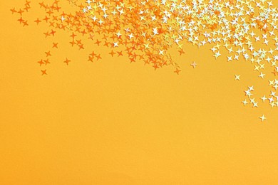 Shiny bright glitter on light orange background, flat lay. Space for text