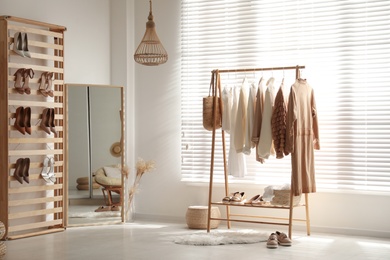 Photo of Modern dressing room interior with racks of stylish women's clothes and shoes