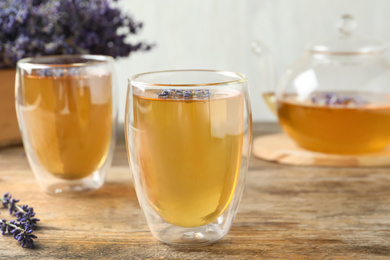 Photo of Fresh delicious tea with lavender in glass on wooden table