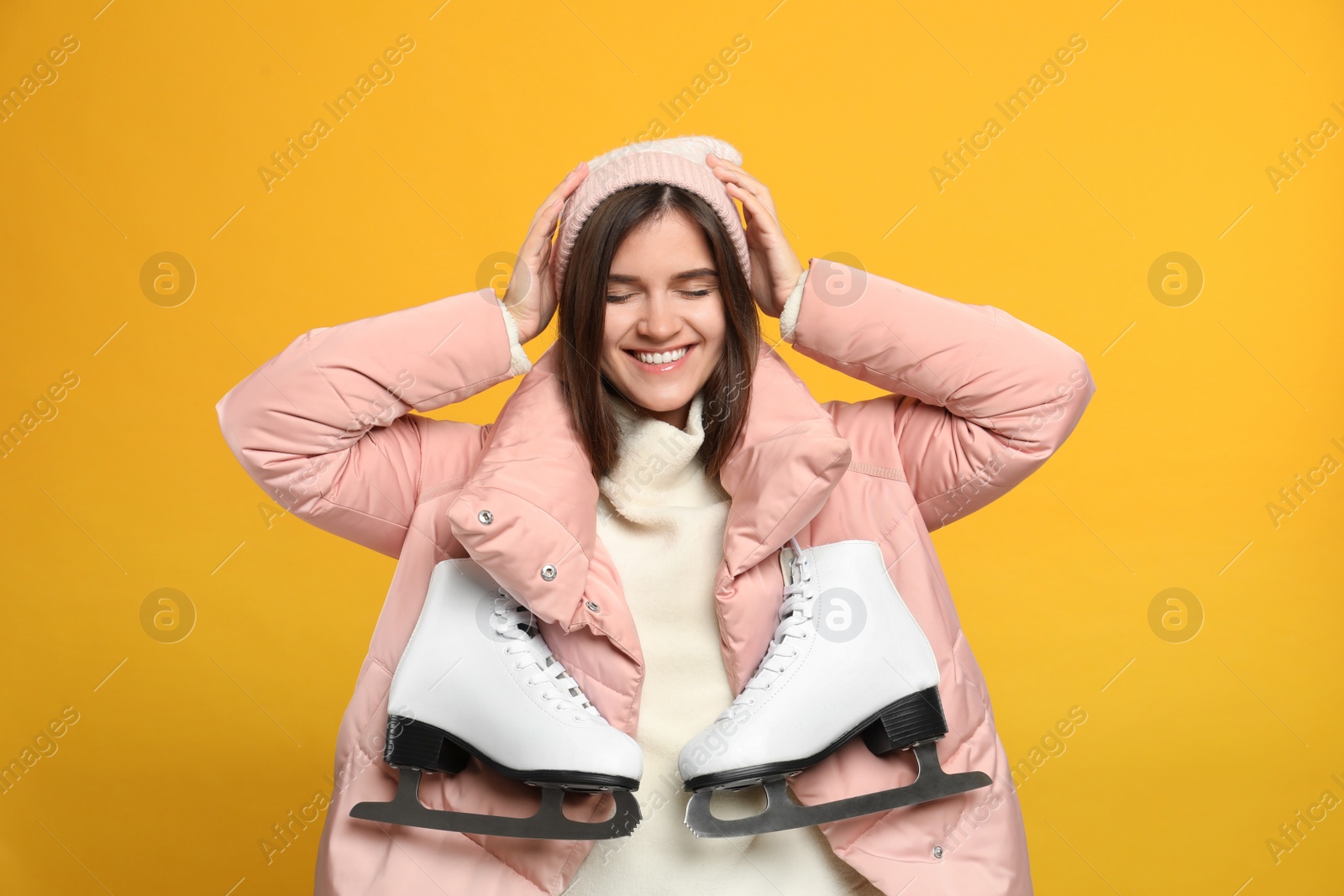 Photo of Happy woman with ice skates on yellow background