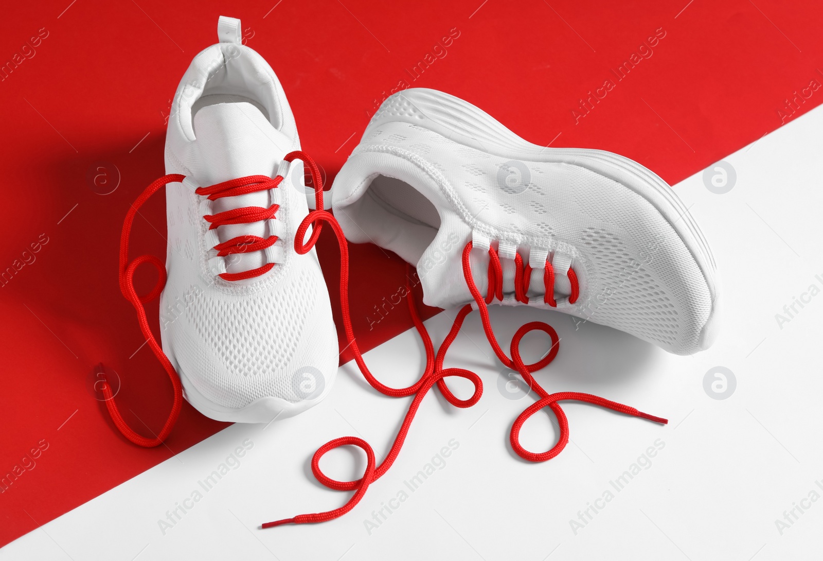 Photo of Pair of stylish shoes with red laces on color background