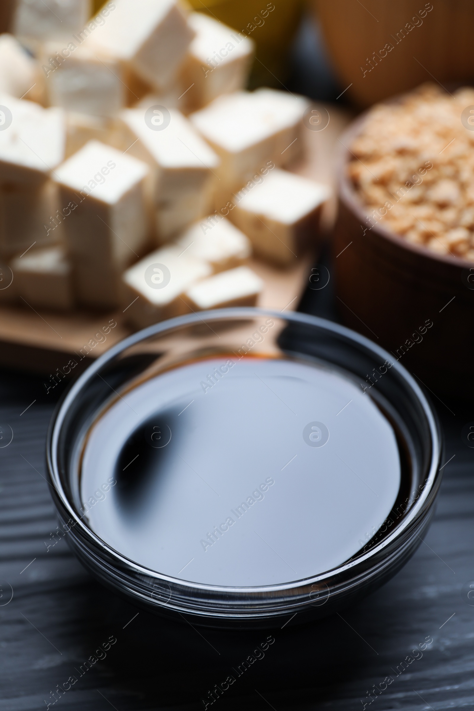 Photo of Soy sauce and other organic products on grey wooden table, closeup