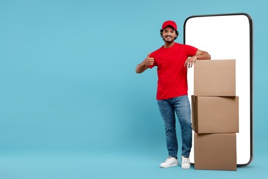 Image of Courier with stack of parcels near huge smartphone on light blue background. Delivery service. Space for text