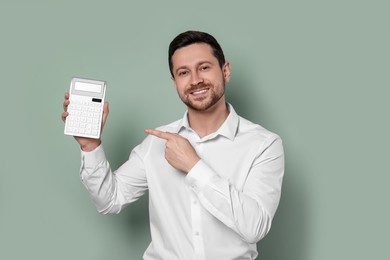 Photo of Happy accountant showing calculator on olive background