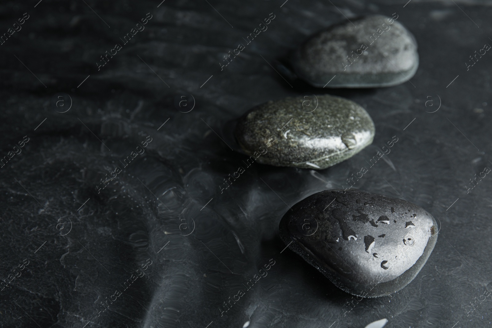 Photo of Stones in water on dark background, space for text. Zen lifestyle