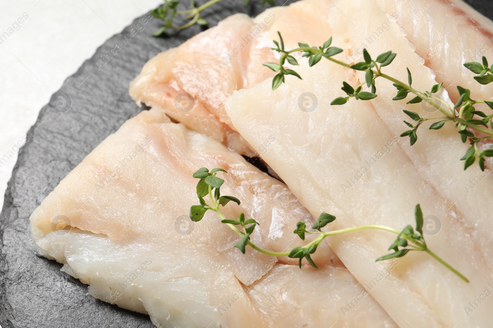 Photo of Pieces of raw cod fish and microgreens on table, closeup