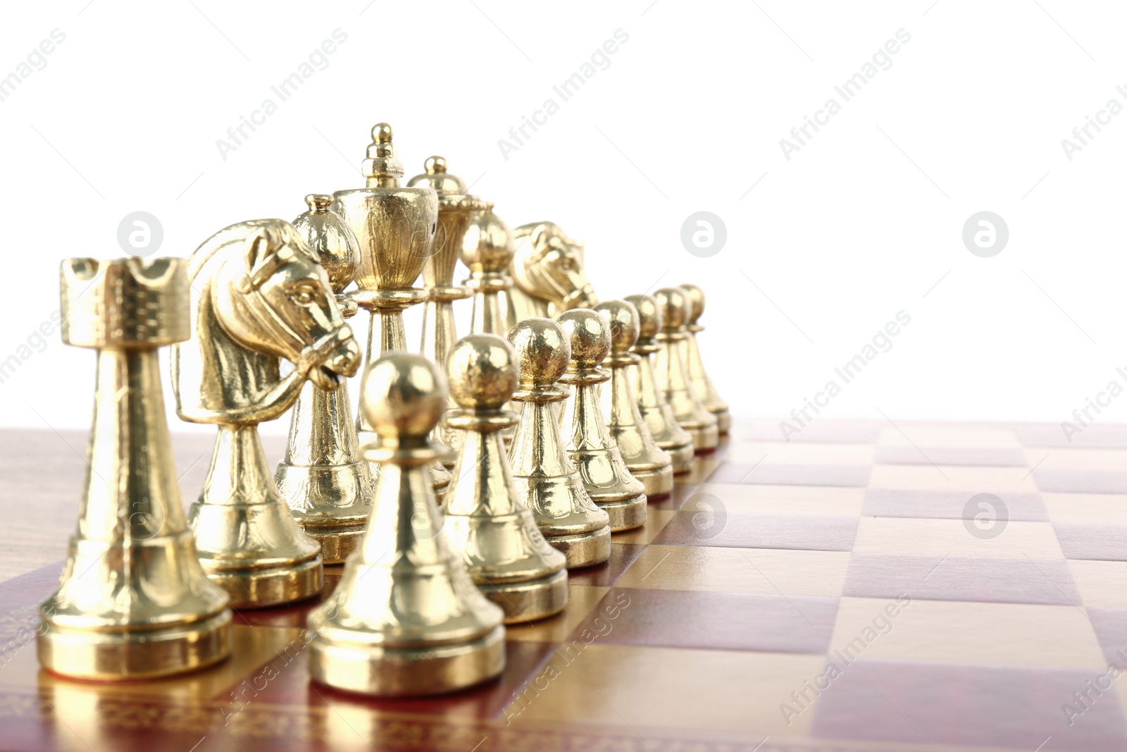 Photo of Set of golden chess pieces on wooden board against white background