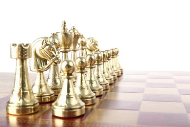 Photo of Set of golden chess pieces on wooden board against white background