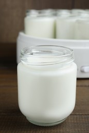 Photo of Glass jar with tasty yogurt on wooden table