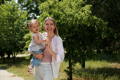 Happy mother with her daughter spending time together in park. Space for text