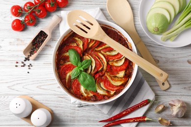 Delicious ratatouille and ingredients on white wooden table, flat lay