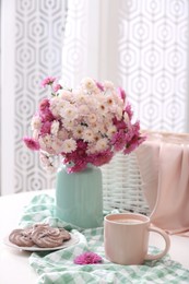 Cup of fresh coffee and beautiful bouquet on white table