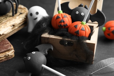 Photo of Different Halloween themed cake pops on black table, closeup