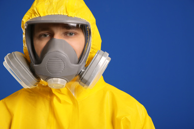 Photo of Man wearing chemical protective suit on blue background, closeup. Virus research