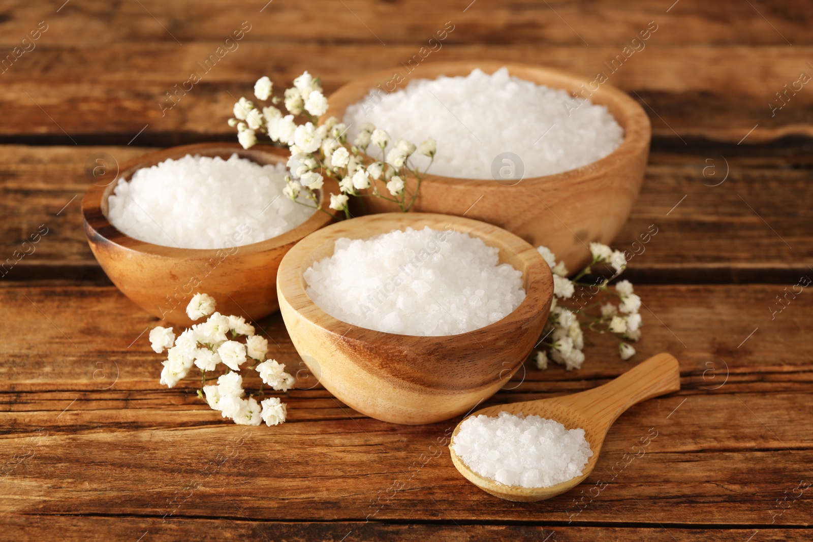 Photo of Aromatic sea salt and beautiful flowers on wooden table