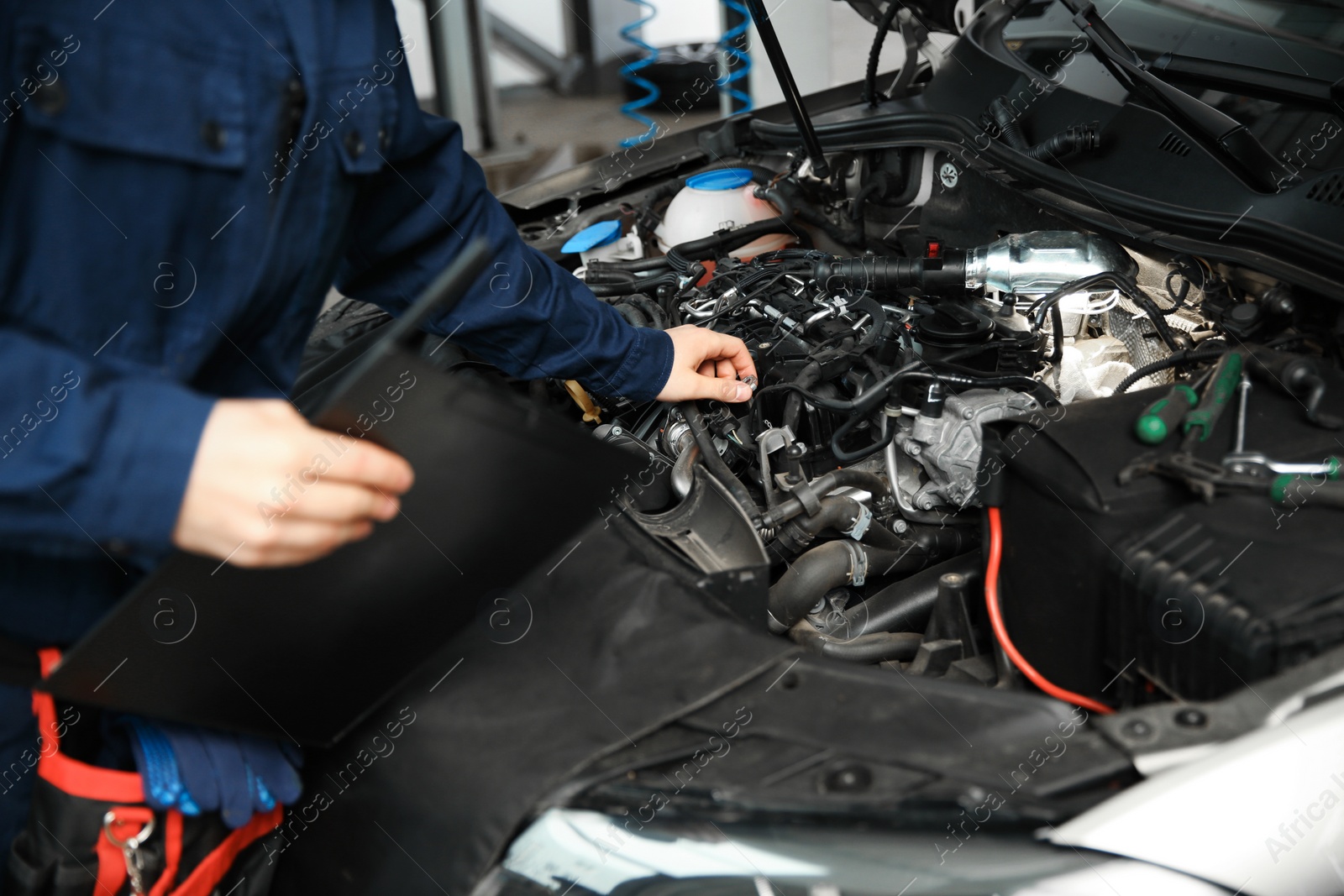 Photo of Technician checking modern car at automobile repair shop, closeup