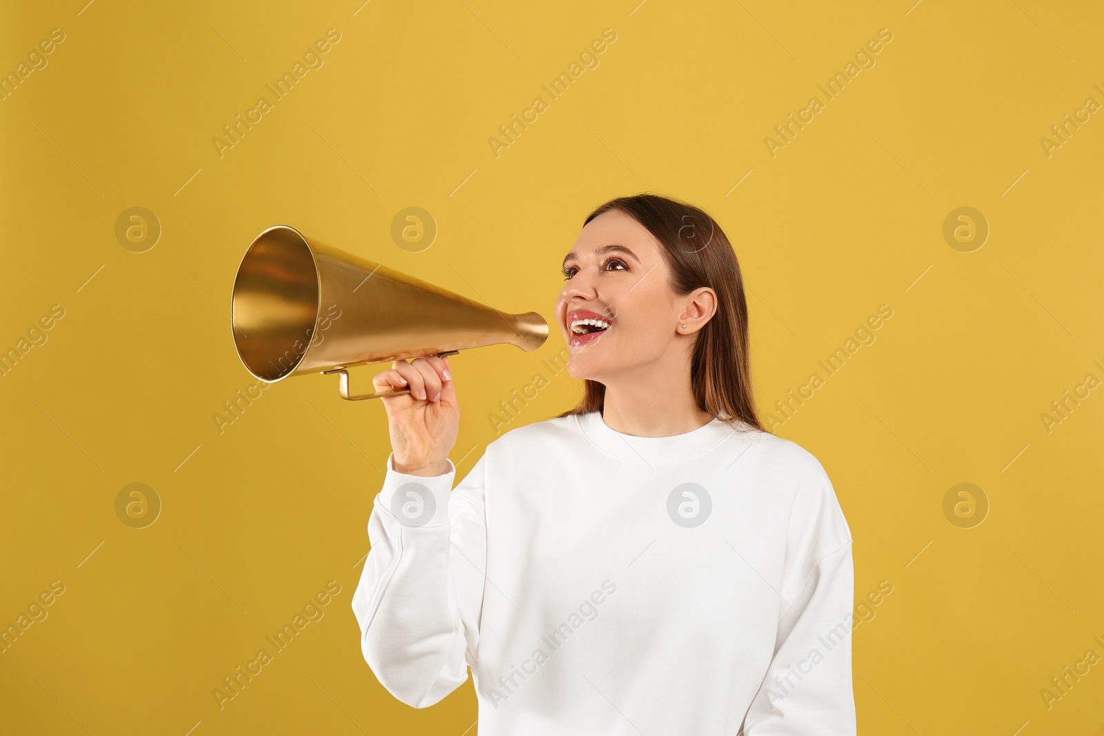 Photo of Young woman with vintage megaphone on yellow background