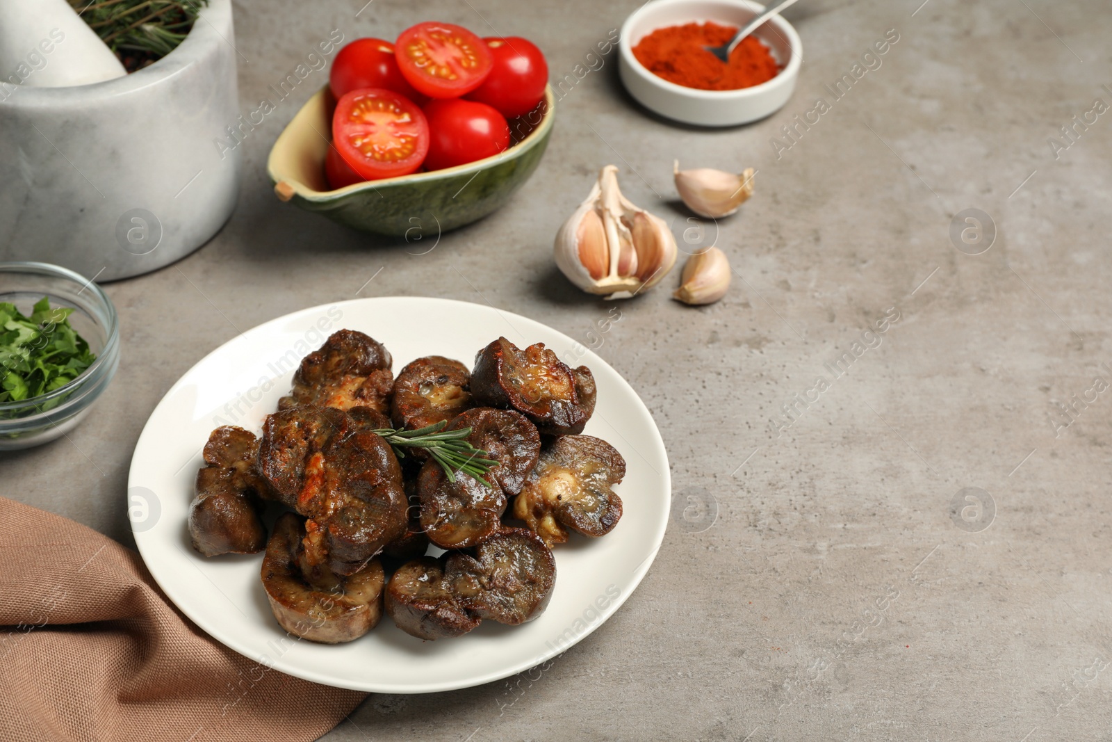 Photo of Delicious kidneys with rosemary and ingredients on light table, space for text
