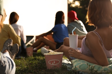 Young woman with popcorn and drink watching movie in open air cinema