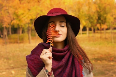 Young beautiful woman with hat and leaf in park. Autumn walk