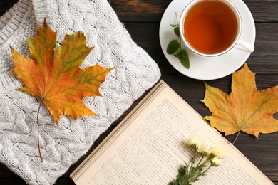 Photo of Flat lay composition with cup of aromatic tea and soft sweater on wooden table. Autumn atmosphere